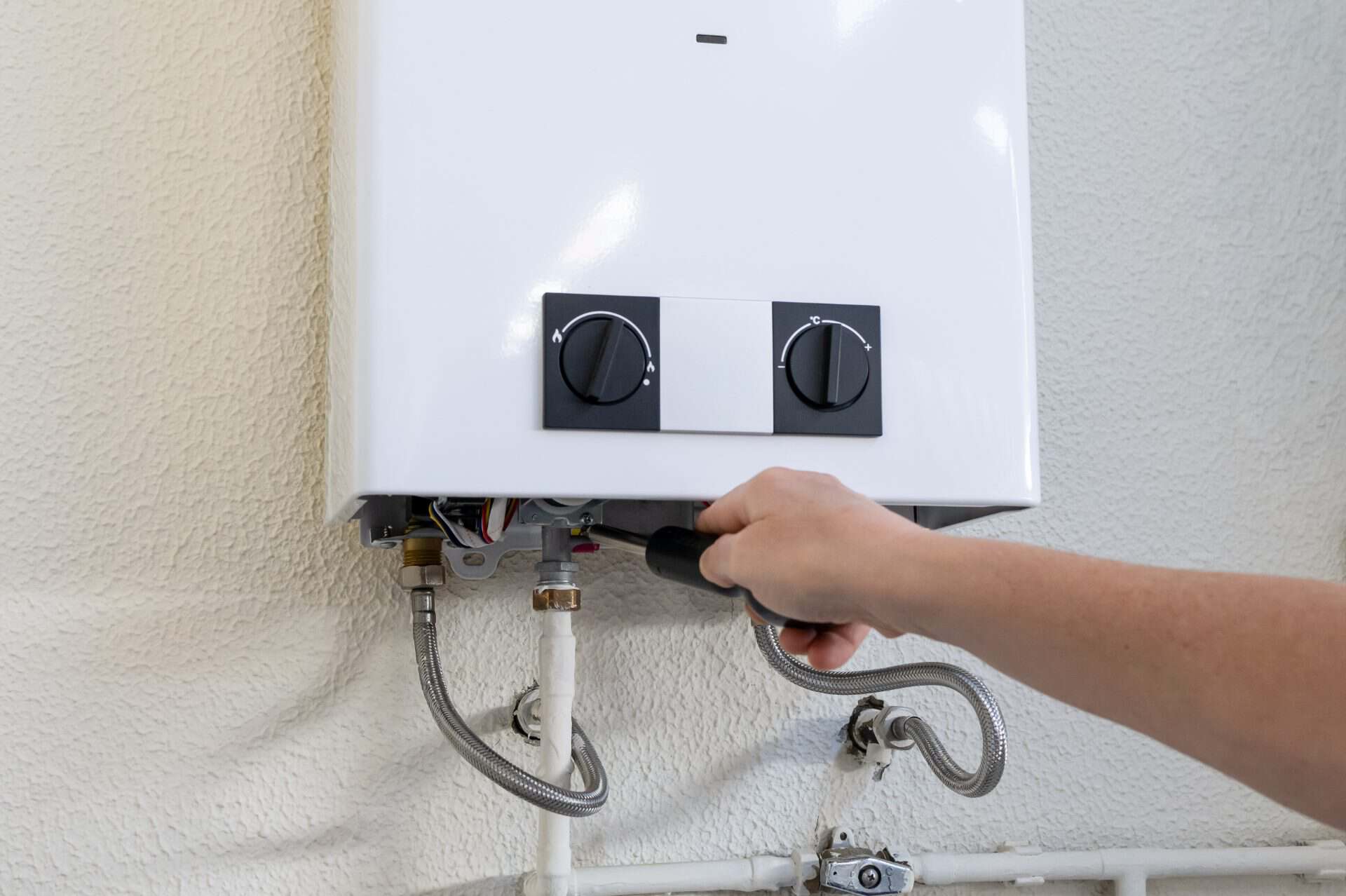 Professional technician using a screwdriver to perform maintenance and repair on a gas water heater, ensuring proper functioning and reliable hot water supply for residential or commercial heating
